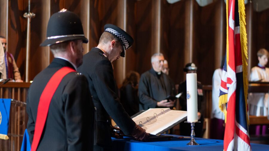 A police officer reads from a folder at a church service